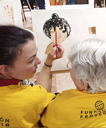 Voluntaria ayudando a pintar un cuadro a una anciana